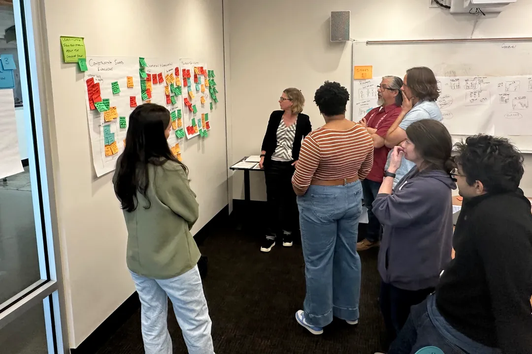 Teachers gathered at a wall of sticky notes and storyboard sketches